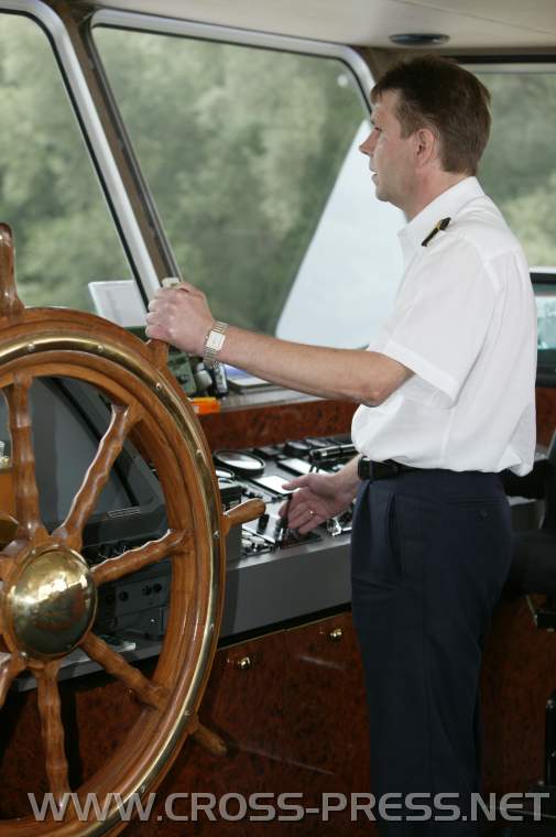 05.08.24_127 Kpt'n Reisinger mit linker Hand auf Riesensteuerrad, das allerdings nur noch Deko-Funktion hat, das Schiff steuert er mit seiner Rechten mittels Minijoystick.