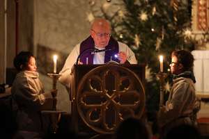 Rorate-Messe in Weistrach Altpfarrer Högl liest aus Evangelium, das er mit Taschenlampe beleuchtet.