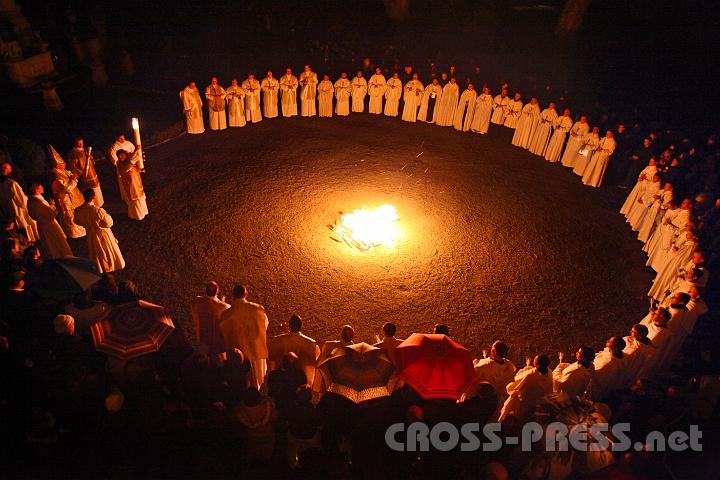 2012.04.07_21.08.08.jpg - Die Osternacht-Feier begann im Stiftshof. Das Feuer spendete nicht nur Licht, sondern auch die benötigte Wärme gegen das kalte Nieseln. Die neue Osterkerze, die ein Jahr lang in der Kirche ihre Dienste leisten wird, hält Diakon Markus Michael Riccabona hoch.