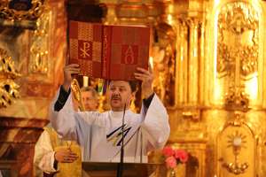 JungFamilienTreffen 2012 Diakon Christian Ganneshofer hebt das Evangeliar hoch vor dem goldenen Altar der Wallfahrtskirche Pöllauberg.