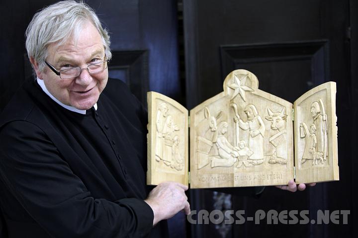 2009.12.03_11.17.20.jpg - P. Martin zeigt eine Besonderheit: seine "kleine Jahreskrippe", 2007 entstanden, deren Teile er jeweils beidseitig geschnitzt hat mit Szenen von der Verkndigung bis zur Himmelfahrt, wobei Geburt und Kreuzigung gro dargestellt sind.