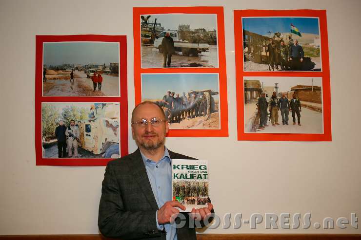 2017.04.07_21.01.14_c.jpg - Wieland Schneider mit seinem 2. Buch. Hinter ihm an der Wand sind Fotos daraus zu sehen.